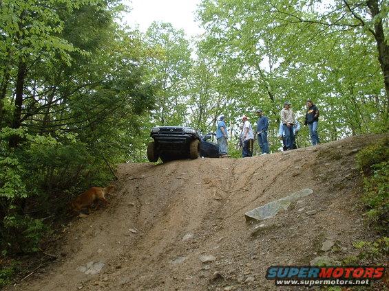 Front view of a black SUV climbing a steep dirt hill; "SUPERMOTORS" text visible