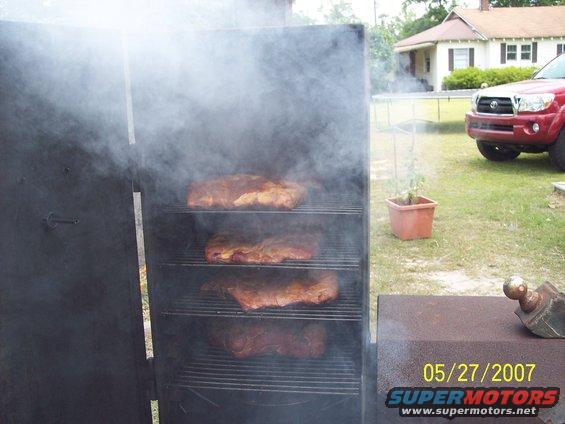 Red Toyota Tacoma parked in yard next to a smoker filled with ribs. Date stamp reads 05/27/2007