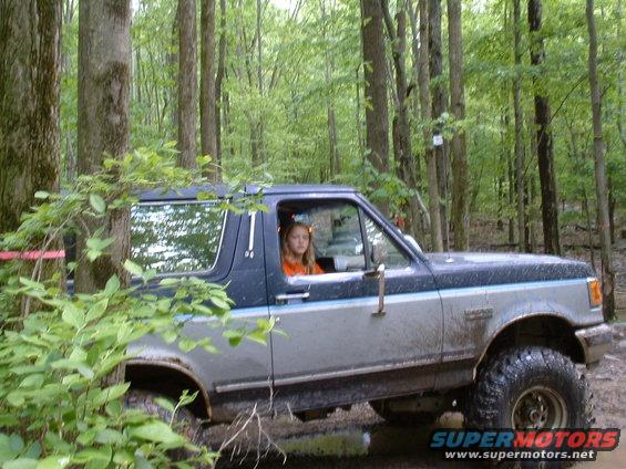 Girl driving a 1991 Ford Bronco on a wooded trail
