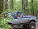 1991 Ford Bronco - A young girl is behind the wheel of a lifted Ford Bronco as it navigates a muddy, wooded path.