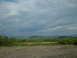 1991 Ford Bronco - A wide landscape view under a dramatic sky, with rolling green hills in the distance.