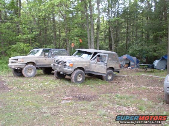 Two 1991 Ford Broncos parked at a campsite with tents in the background