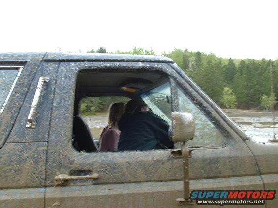 Mud-covered 1987 Ford Bronco side view with two people inside