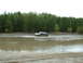 1991 Ford Bronco - An SUV navigates through a muddy water obstacle, surrounded by a dense forest.