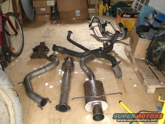 exhaust pipes, catalytic converter, and muffler laid out on a floor