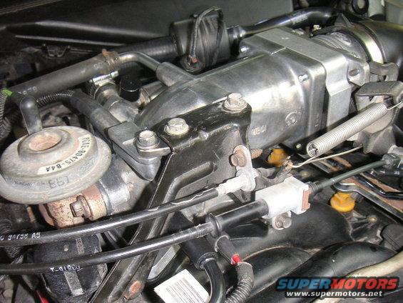 Engine components with hoses, cables, and a silver throttle body