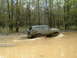 1991 Ford Bronco - A muddy 1987 Ford Bronco navigates a water obstacle in a forest setting.