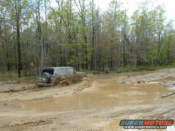 Brown 1991 Ford Bronco stuck in mud, rear view