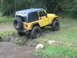2001 Jeep Wrangler - A yellow Jeep Wrangler navigates a muddy trail next to a stream.