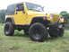 2001 Jeep Wrangler - Yellow 2001 Jeep Wrangler with off-road tires sits on grassy terrain.