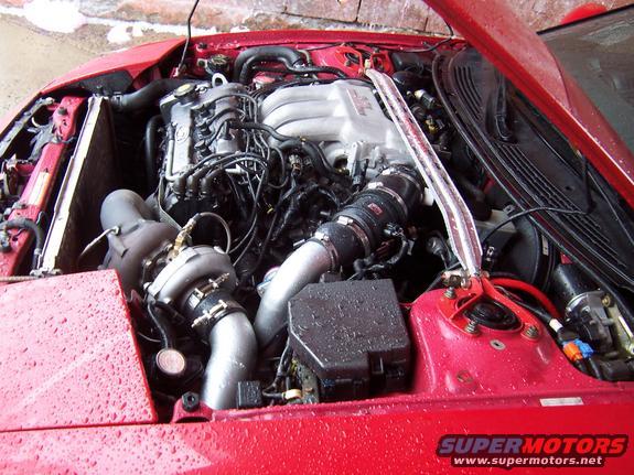 Engine bay with aftermarket turbocharger and intercooler piping. Red car