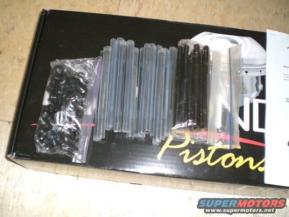 Box of engine parts including small black clips, clear tubes, and black rods