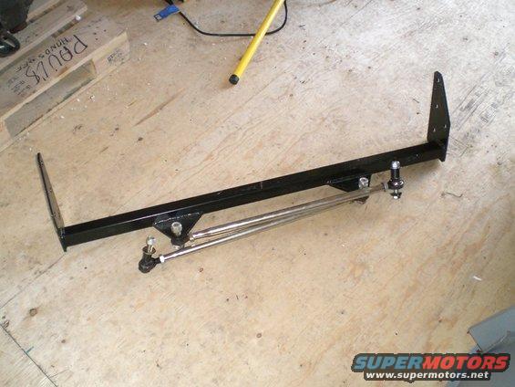Black metal traction bars with adjustable rods and ball joints on a wooden floor