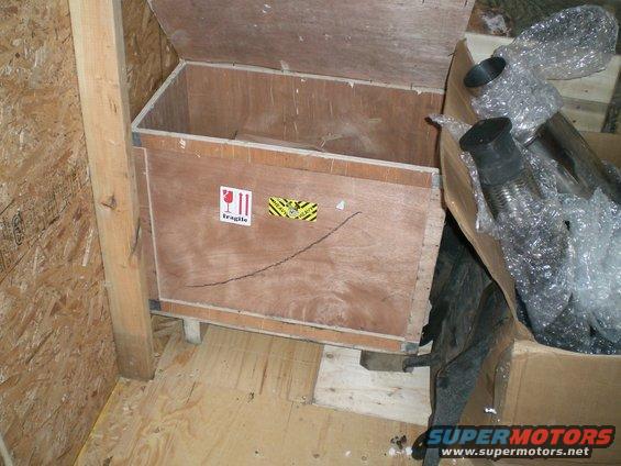 Wooden crate with fragile sticker, containing exhaust parts wrapped in bubble wrap