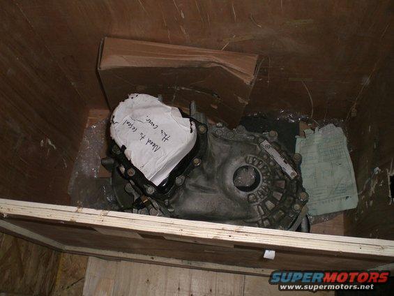 Transmission casing with a note that says 'Need to reseal. This cover.' inside a wooden crate