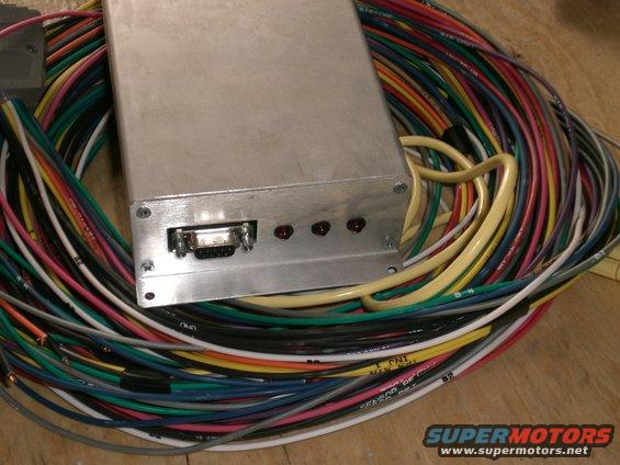 Aluminum box with DB9 connector and red LEDs, surrounded by a large bundle of multicolored wires