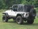 2001 Jeep Wrangler - A white Jeep Wrangler is parked on a grassy area next to a body of water, with trees in the background.