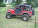 2001 Jeep Wrangler - This red 2001 Jeep Wrangler is seen from a 3/4 front angle, equipped with a soft top and spare tire on the rear.