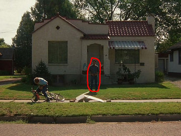 Person in front of a house with a bicycle on the lawn