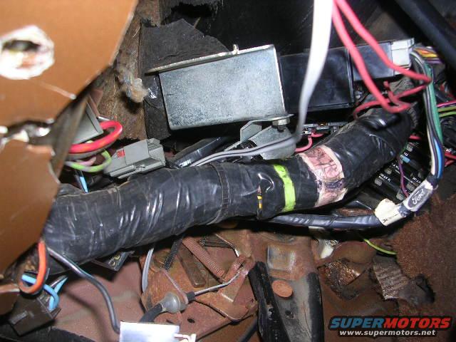 close-up of a vehicle's wiring harness with black tape and some Ford branding visible