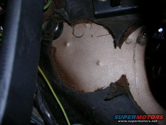 Close-up of a tan interior car panel with visible damage and wiring