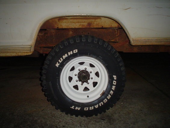 Kumho Powerguard MT tire on white rim, showing rusty fender and body panel