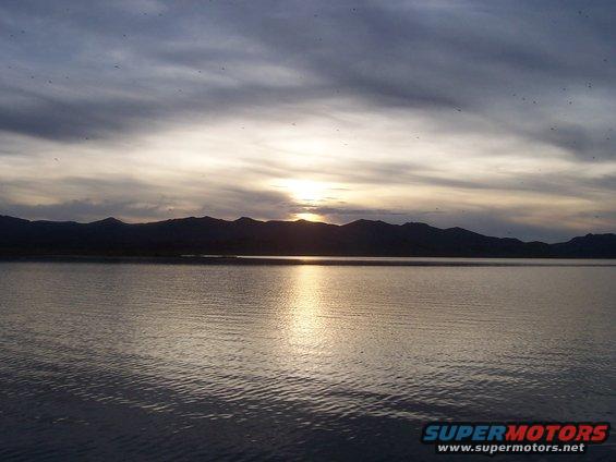 Lake and mountains at sunset with a Supermotors watermark