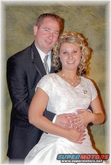 Groom in suit hugs bride in wedding dress. They are smiling