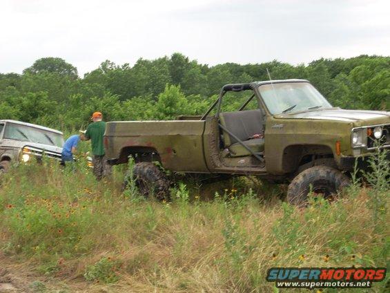Olive green off-road pickup truck with roll cage, front 3/4 view