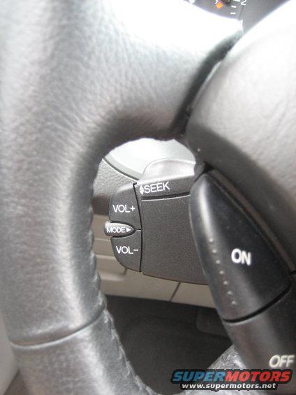 Steering wheel with audio controls labeled SEEK, VOL+, MODE, VOL-, ON, and OFF. Part of a dashboard is visible