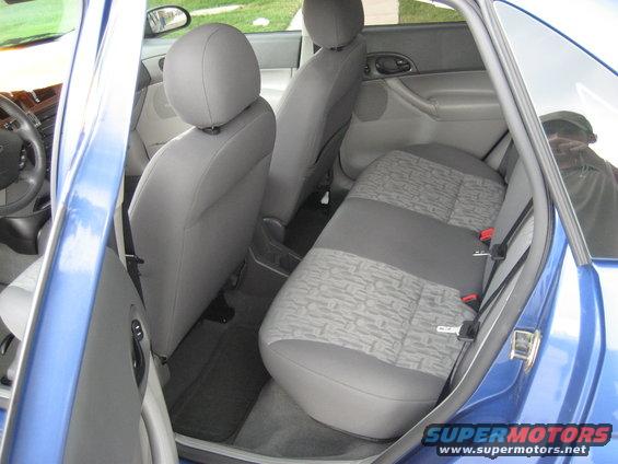 Interior view of a blue car showing front and rear seats, door panels, and steering wheel