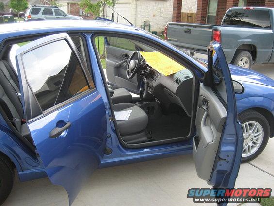 Blue sedan interior with doors open, yellow paper on dashboard