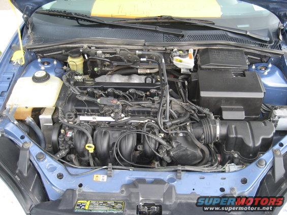 engine bay of a blue car, showing engine components and wiring