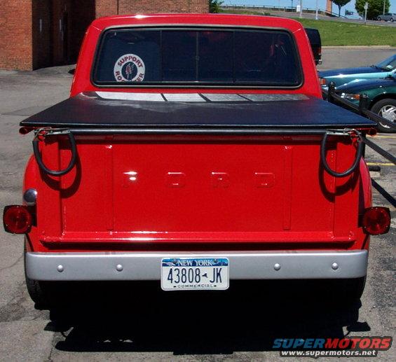 Red Ford pickup truck rear view with black tonneau cover and New York license plate