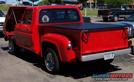 Red Ford pickup truck with hood open, black tonneau cover, and chrome bumper. License plate reads 43608-JK