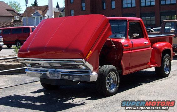 Red pickup truck with hood open, chrome grille, and visible license plate