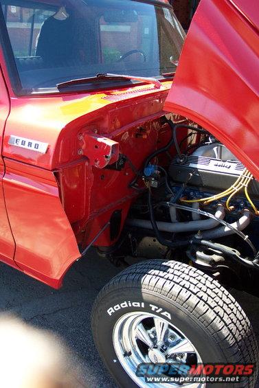 Red Ford truck engine bay with hood open, chrome wheels, and 'Radial T/A' tire