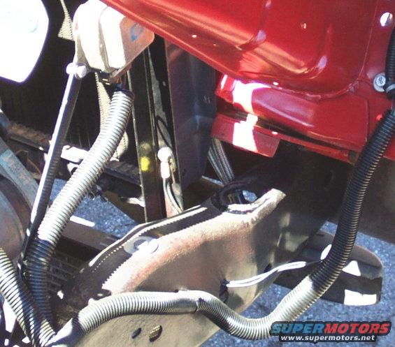 Close-up of vehicle chassis with red body panel and black wiring conduits