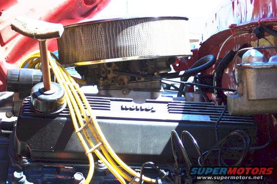 Close-up of a V8 engine with a Holley carburetor, air cleaner, and yellow spark plug wires