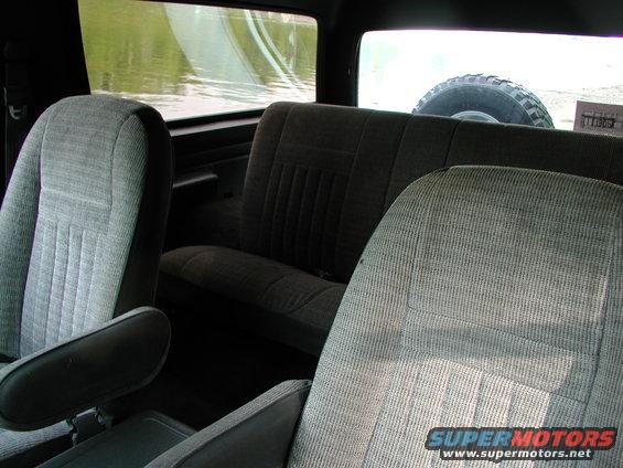 Interior view of a Ford Bronco with cloth seats and a spare tire visible through the rear window
