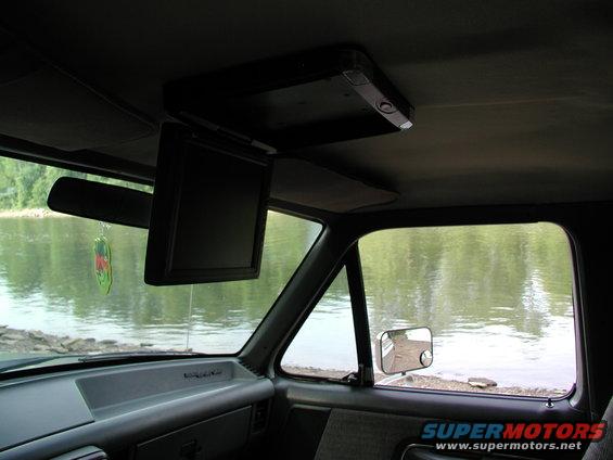 Interior view of a vehicle with a flip-down screen, showing a river outside the window