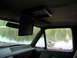 1989 Ford Bronco - The interior of a vehicle is shown, with a screen mounted overhead and a view of a river through the side window.