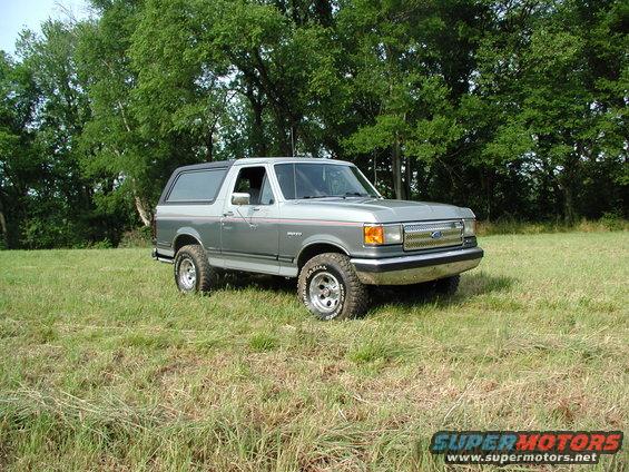 Ford Bronco parked in a grassy field with trees in the background