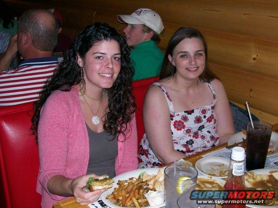 Two women and a guy in a hat at a restaurant table with food