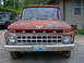 1965 Ford F-100 - Front view of a red 1965 Ford F-100 truck with a police car in the background.