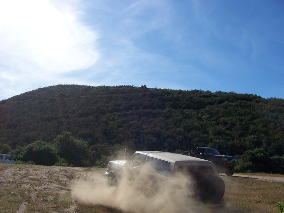 White 1991 Ford Bronco driving off-road, kicking up dust