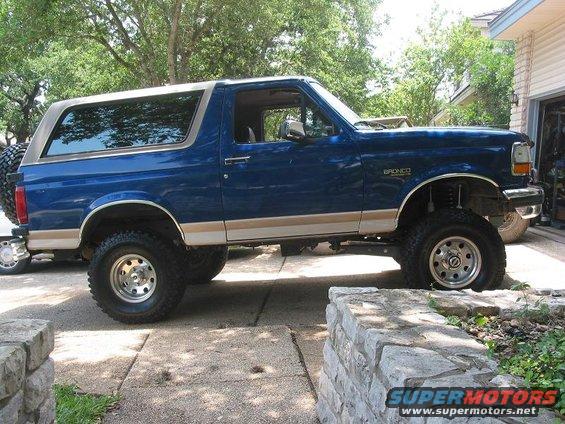 Blue 1996 Ford Bronco with tan trim and lifted suspension, parked on a driveway