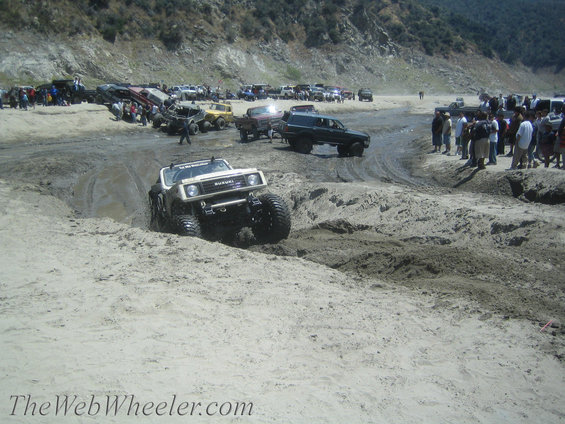 1987 Suzuki Samurai navigating a muddy off-road course with large tires