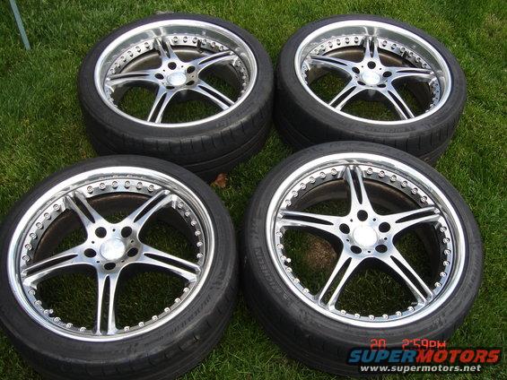 Four chrome five-spoke alloy wheels with tires on grass