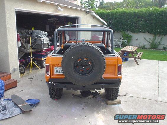 Orange 1977 Ford Bronco parked in driveway, rear view with spare tire mounted